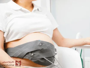 خانم باردار با کمربند مانیتورینگ قلب جنین بر روی شکم در حال انجام نوار قلب جنین